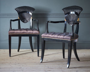 six black dining chairs with a scalloped back and mauve buttoned silk seats