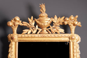 a gilt framed mirror with a carved urn and leaves
