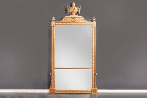 a large gilt frame mirror with flower heads in each corner and urn frieze on top