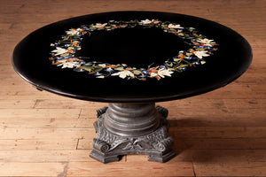 a black circular table with a ring of colourful floral inlays