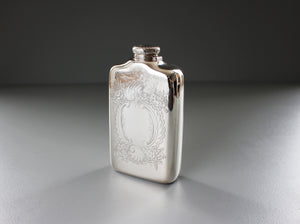 a silver flask with floral etchings